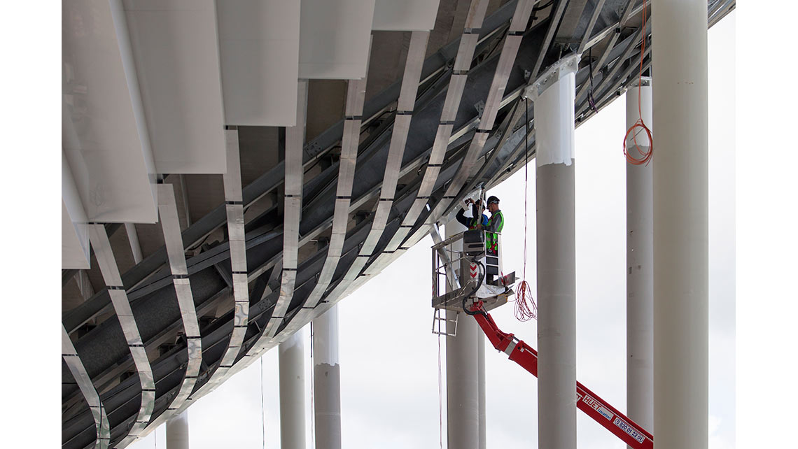 Deux ouvriers travaillent à la mise en place de l'habillage de la charpente métallique des gradins sur le chantier du stade Matmut Atlantique de Bordeaux ; © Richard Nourry