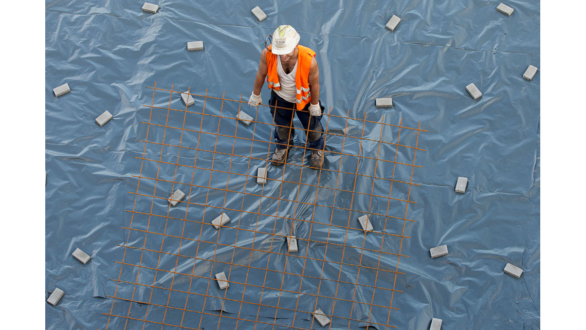 Sur le chantier du magasin IKEA de Bayonne, vue en plongée d'un ouvrier réalisant l'étanchéité du sol ; © Richard Nourry