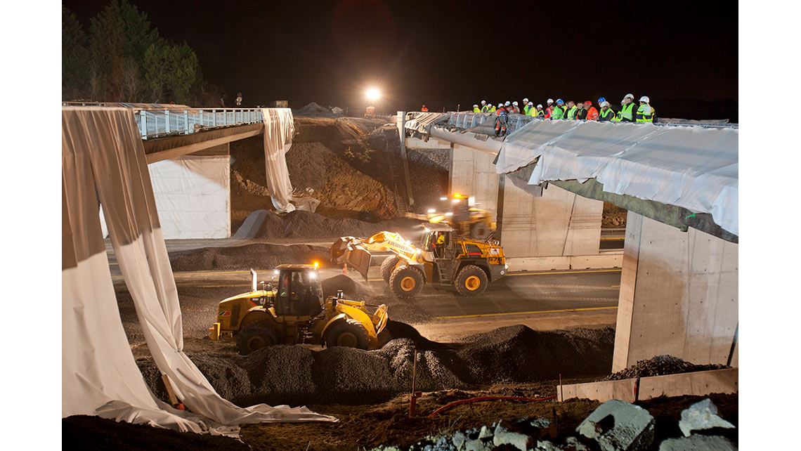 De nuit sur le chantier de l'A63, deux engins de terrassement préparent la démolition d'un pont sous l'oeil des ouvriers ; © Richard Nourry