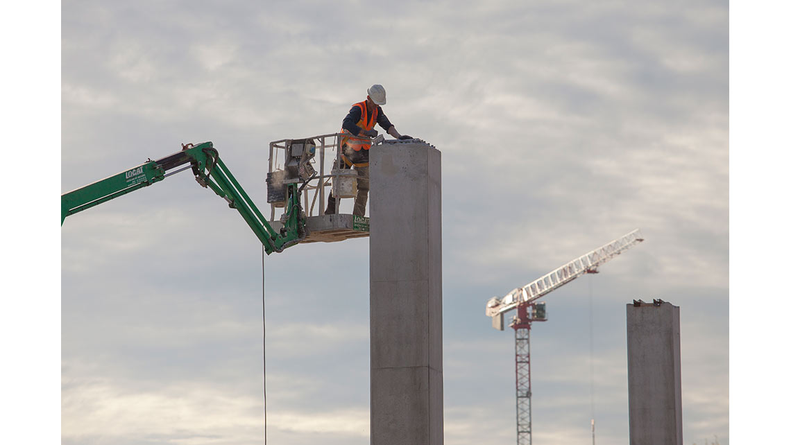Un maçon dans une nacelle travaille au sommet d'un pilonne de soutien de la charpente sur le chantier du magasin IKEA de Bayonne ; © Richard Nourry
