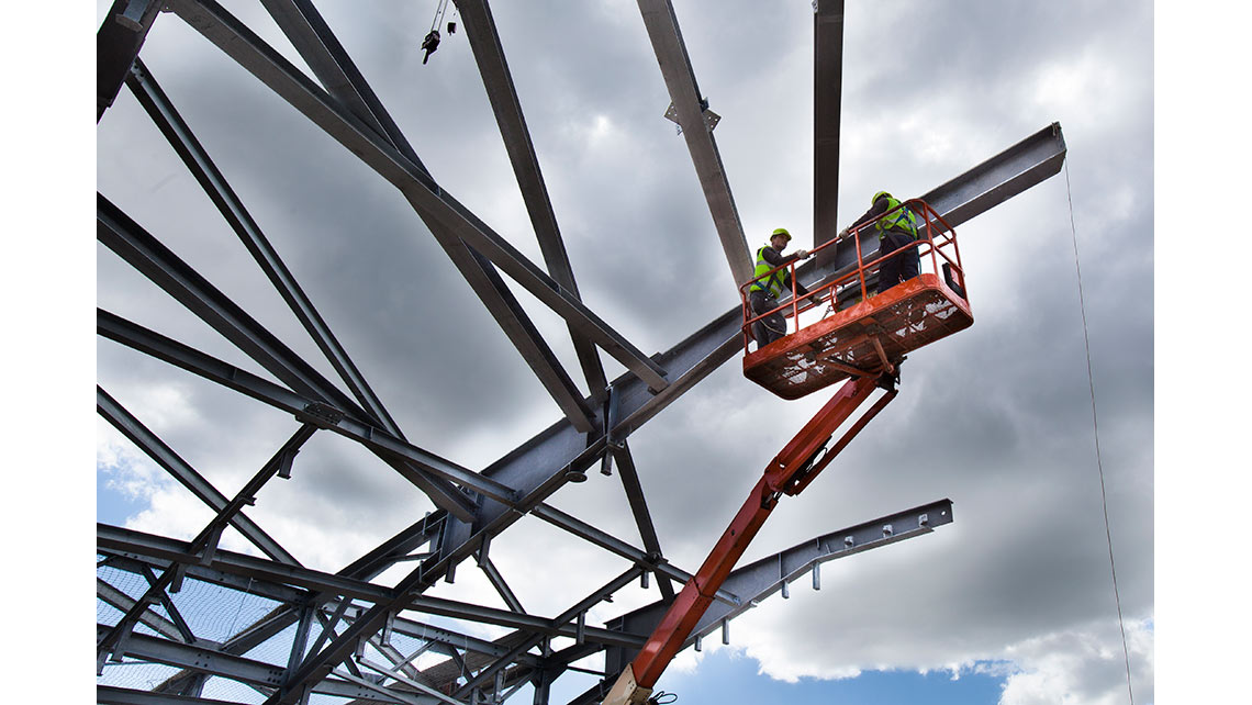 Deux ouvriers dans une nacelle préparent la levée de la charpente de la tribune d'angle sur le chantier du stade Matmut Atlantique de Bordeaux ; © Richard Nourry