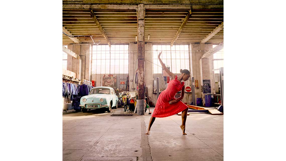 Portrait d'Alix, danseuse jazz au Conservatoire de Bordeaux, exécutant un pas de danse dans un atelier de réparation automobile. © Richard Nourry