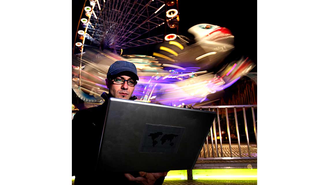 Portrait de nuit de Rafa, élève au Conservatoire de Bordeaux, composant de la musique la nuit sur un ordinateur portable devant des manèges. © Richard Nourry