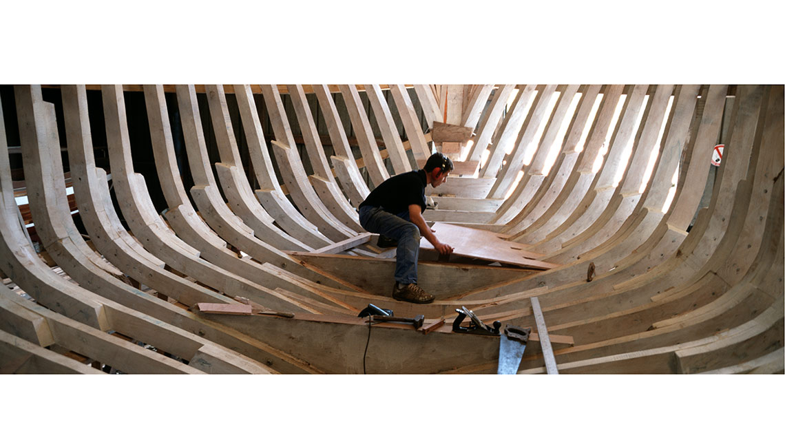 Charpentier de marine dans l'étrave d'un bateau en bois en construction au chantiers Tanguy de Douarnenez ; © Richard Nourry