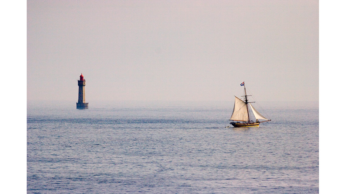 Un vieux grément navigue devant le phare de la Jument près d'Ouessant ; © Richard Nourry