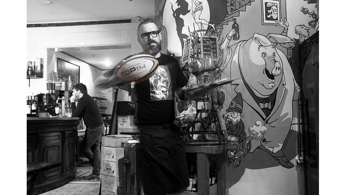 Portrait d'un barman tenant un ballon de rugby dans son établissement, © Richard Nourry
