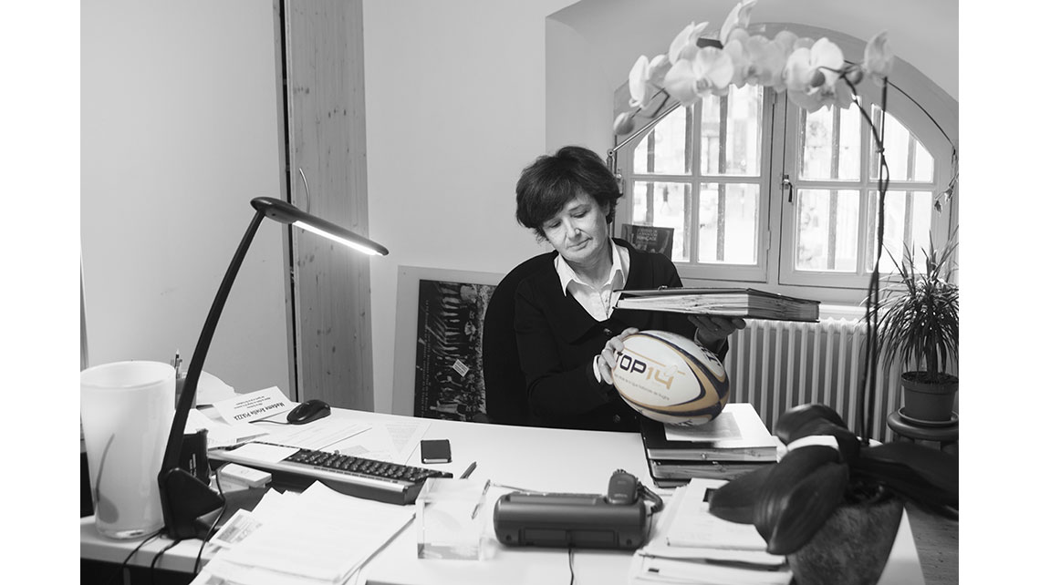 Portrait d'Arielle tenant un ballon de rugby placé sur son bureau, © Richard Nourry