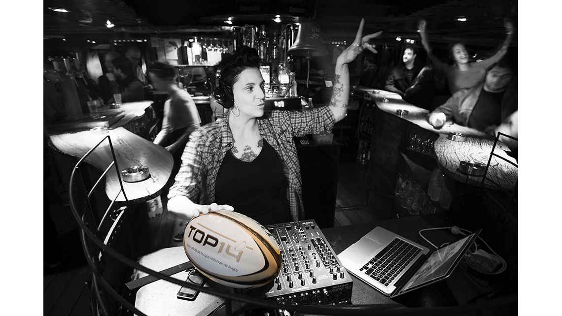 Portrait d'une DJ avec un ballon de rugby placé sur sa table de mixage dans un club, © Richard Nourry